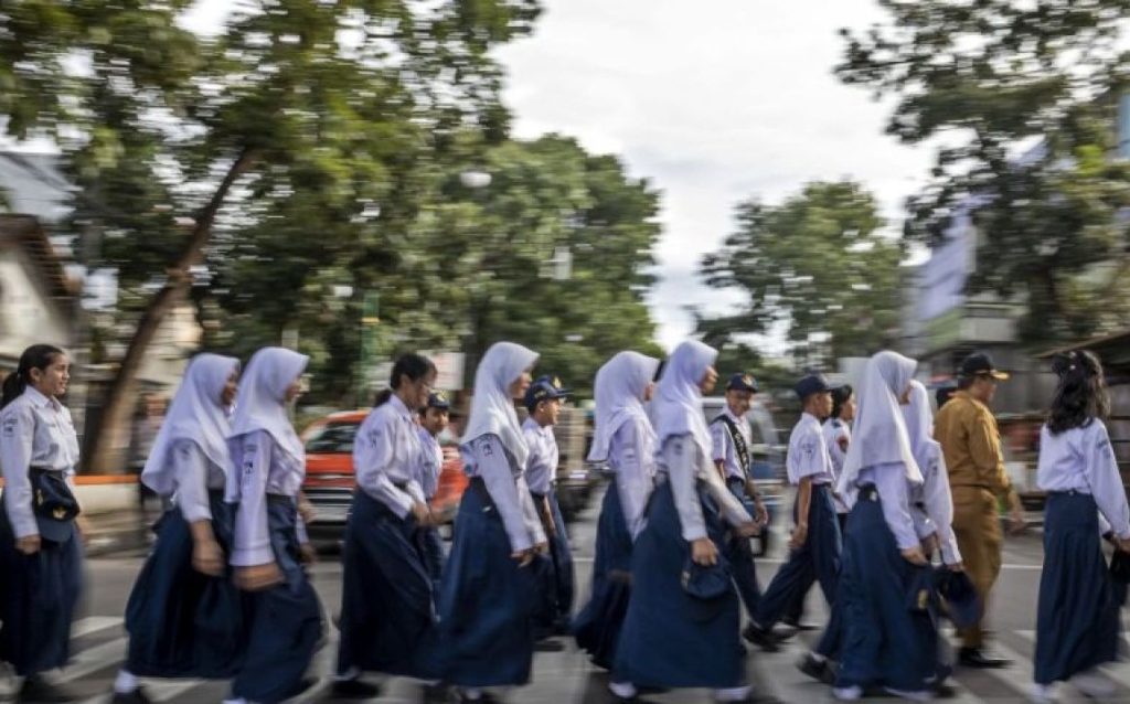 Sejumlah pelajar didampingi petugas Dinas Perhubungan (Dishub) Kota Cimahi menyeberang jalan di Pelican Crossing di Jalan Gatot Subroto, Kota Cimahi, Jawa Barat, Senin (19/1/2026). Dinas Perhubungan (Dishub) Kota Cimahi melakukan uji coba dan sosialisasi penggunaan Pedestrian Light Controlled Crossing (Pelican Crossing) sebagai upaya menciptakan jalur aman untuk menyeberang serta mengurangi risiko kecelakaan.