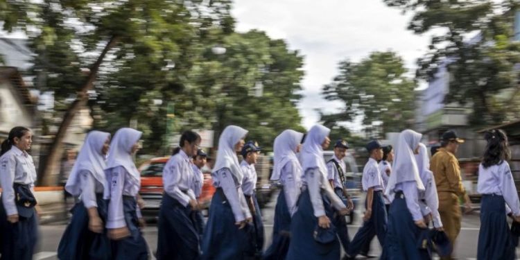 Sejumlah pelajar didampingi petugas Dinas Perhubungan (Dishub) Kota Cimahi menyeberang jalan di Pelican Crossing di Jalan Gatot Subroto, Kota Cimahi, Jawa Barat, Senin (19/1/2026). Dinas Perhubungan (Dishub) Kota Cimahi melakukan uji coba dan sosialisasi penggunaan Pedestrian Light Controlled Crossing (Pelican Crossing) sebagai upaya menciptakan jalur aman untuk menyeberang serta mengurangi risiko kecelakaan.